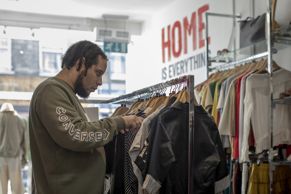 A volunteer in a Shelter shop looks through a rail of shirts