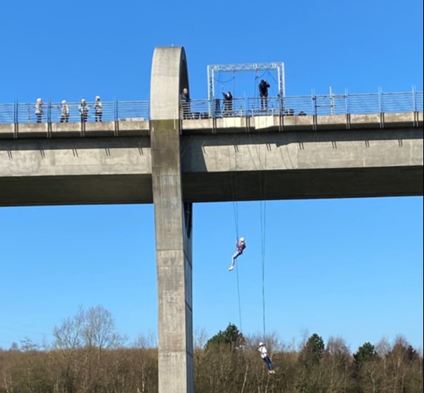 Two people abseiling from Falkirk Wheel, with family and friends watching at the bottom.