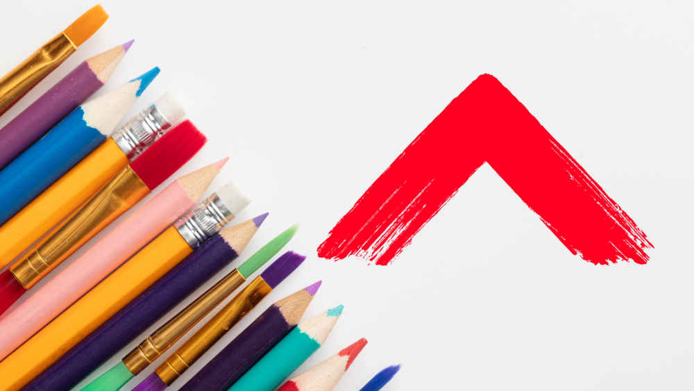 A selection of pencils and paintbrushes next to the Shelter Scotland logo