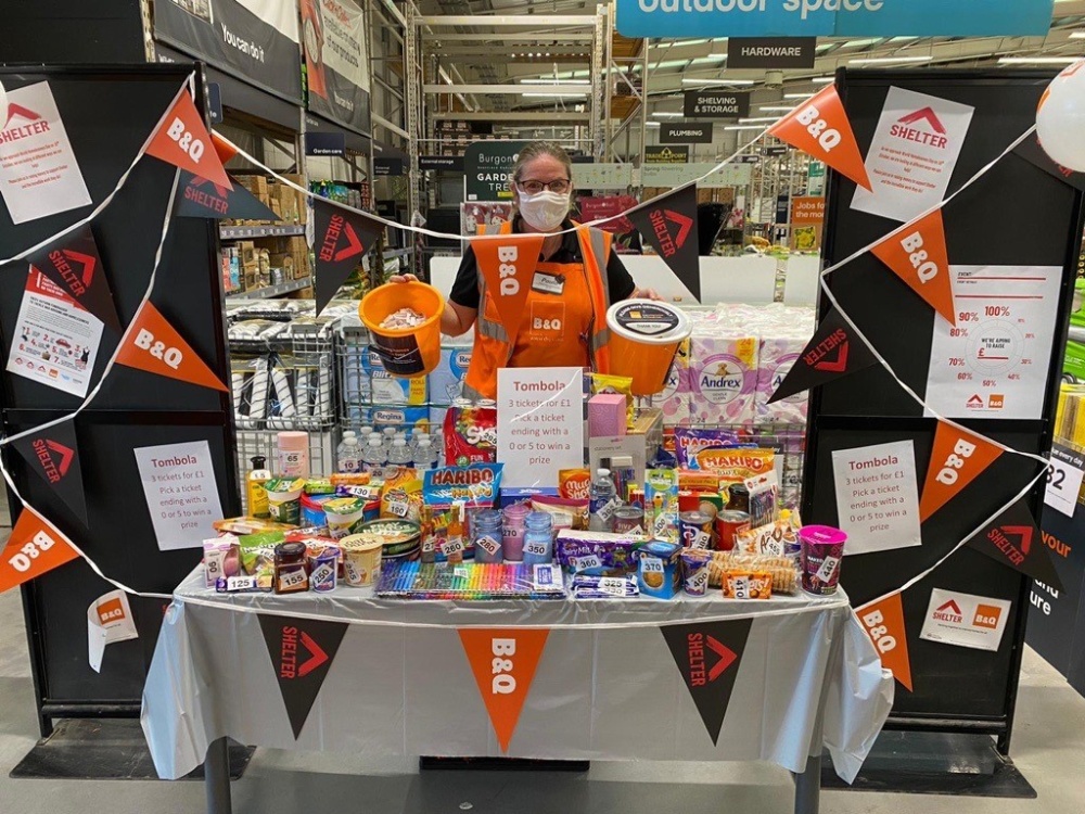 A stall inside B&Q with confectionery and dual branded bunting. A member of B&Q staff is behind the stall holding donation buckets.