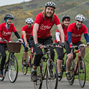 People cycling while wearing charity branded tops.