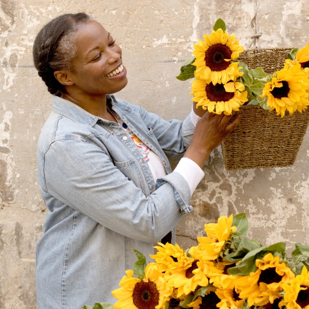 A woman smiling next to a basket of sunflowers