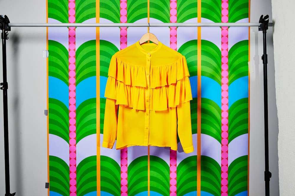 yellow blouse on hanging rail against colourful background