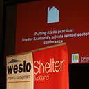 A Shelter Scotland presentation with branded pop-up banners in front of it. 
