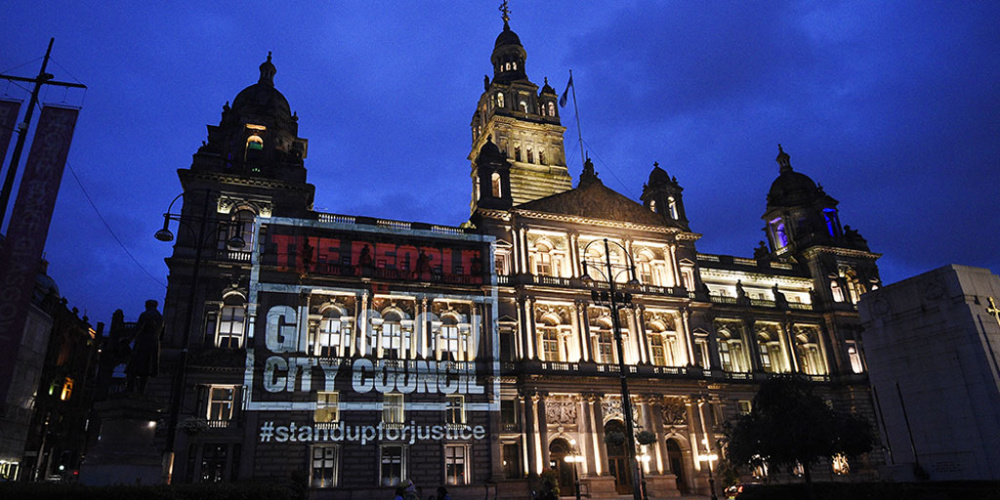 A projection of 'The People v Glasgow City Council' onto Glasgow's City Chambers at night.