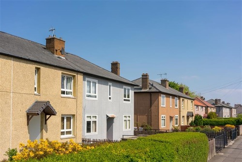 A row of Scottish social homes, with gardens and flowers, and a bright blue sky behind