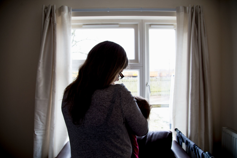 Aly, a service user at the Shelter Scotland Support Service in Dumfries & Galloway. Photographed for Shelter Scotland's 50th anniversary by Yeong Yao Ting. Mother and baby, back to camera, window.