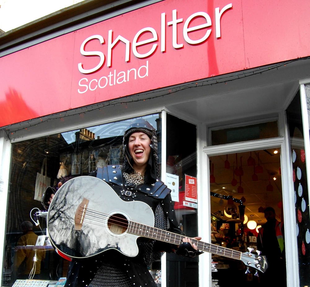 Someone outside Shelter Scotland's Stockbridge shop wearing a warrior costume and holding a guitar. 