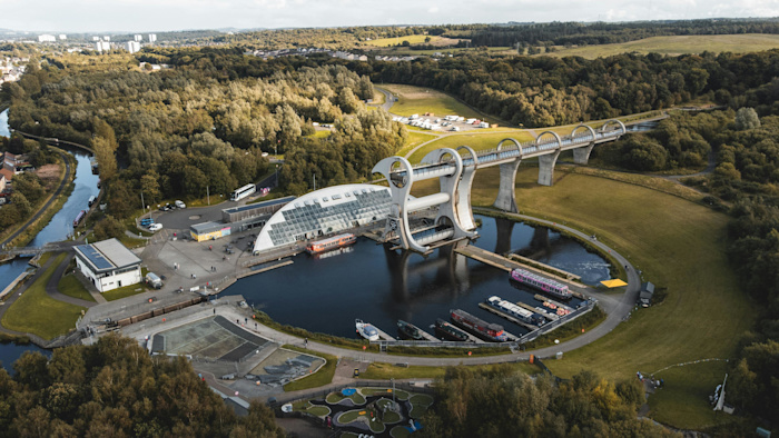 A bird's eye view of Falkirk Wheel at the centre of a circular harbour lined by boats.