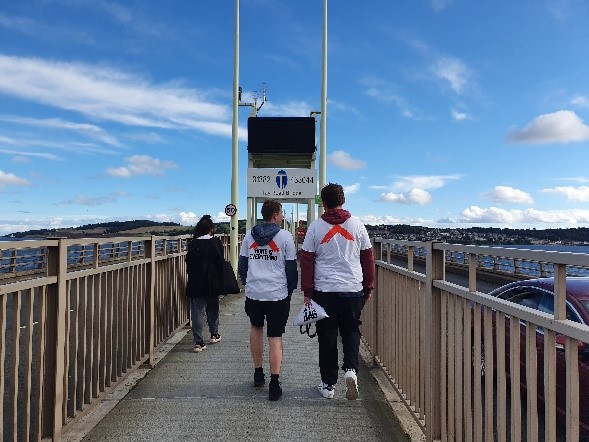 Two Shelter Scotland and B&Q fundraisers walk across a bridge