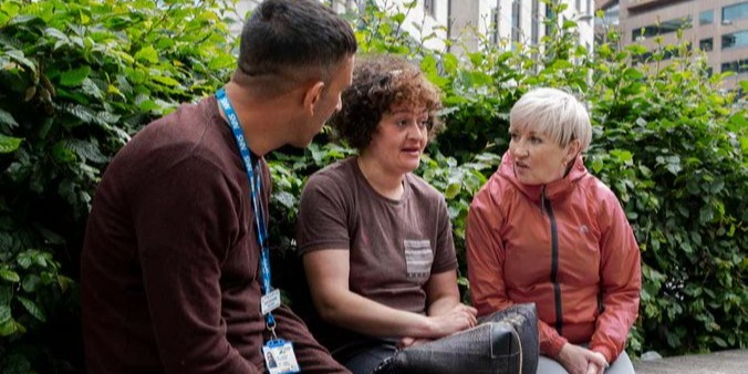 Three people talking outside.