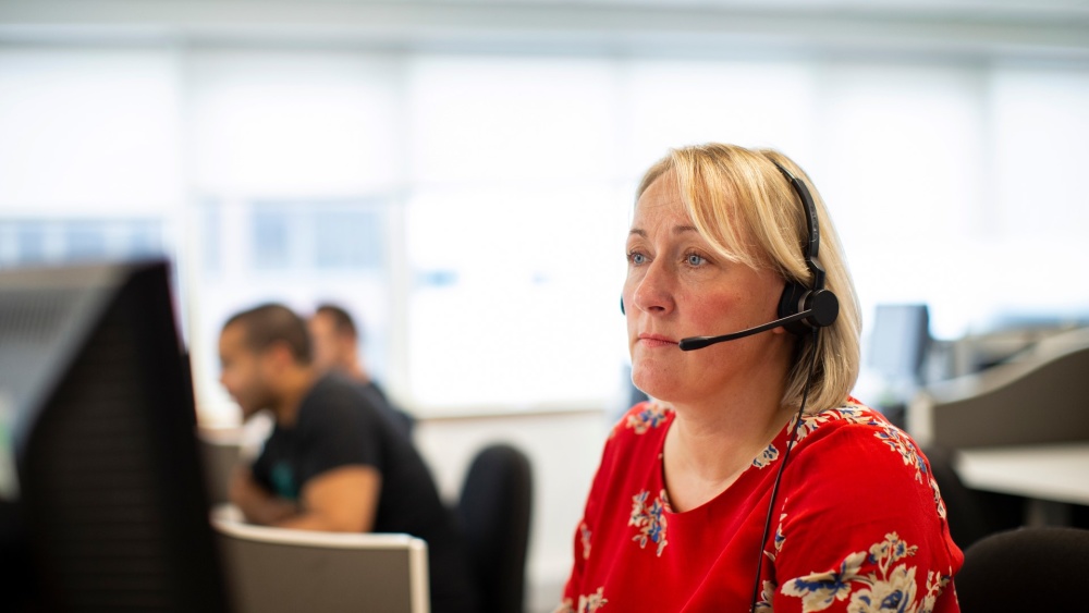 A Shelter helpline adviser on a call, wearing a headset