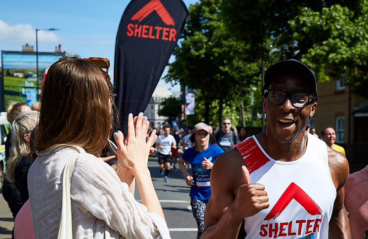 A runner wearing a Shelter vest gives a thumbs up
