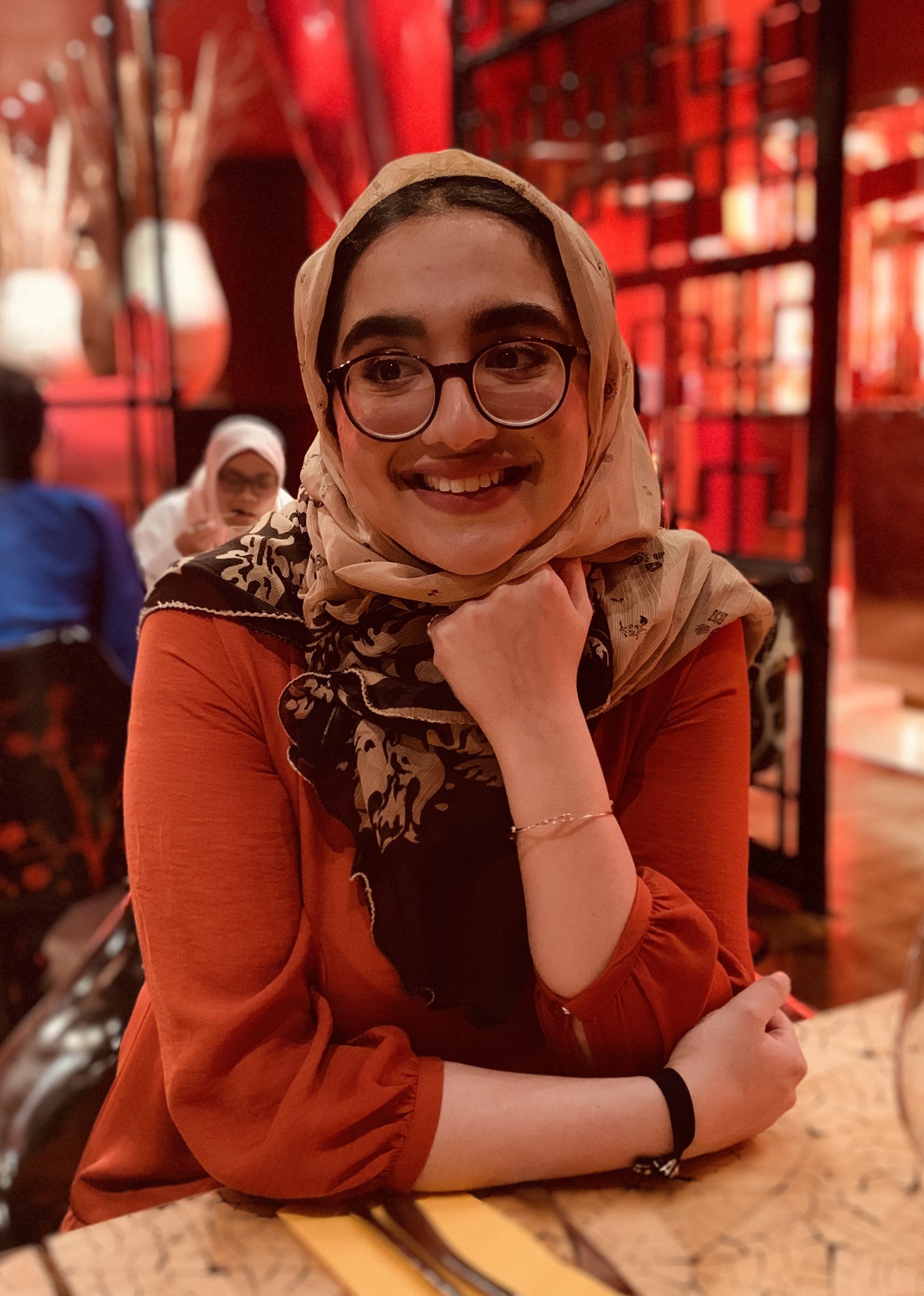 Arshmeena Durrani is a Shelter Board trustee. Arshmeena wears glasses and smiles. She wears a head scarf and presses her chin onto her fist. 