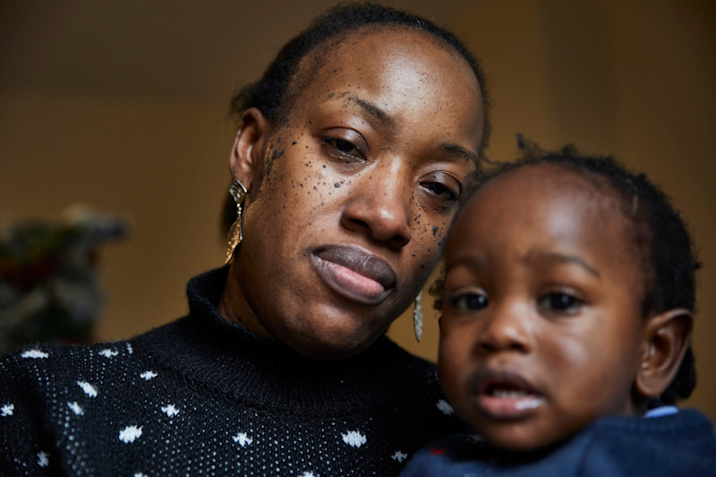 A Black woman holding her baby and looking at the camera