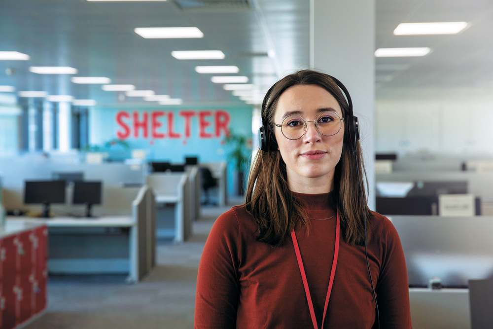 One of our helpline advisers, wearing a headset looking directly into the camera 