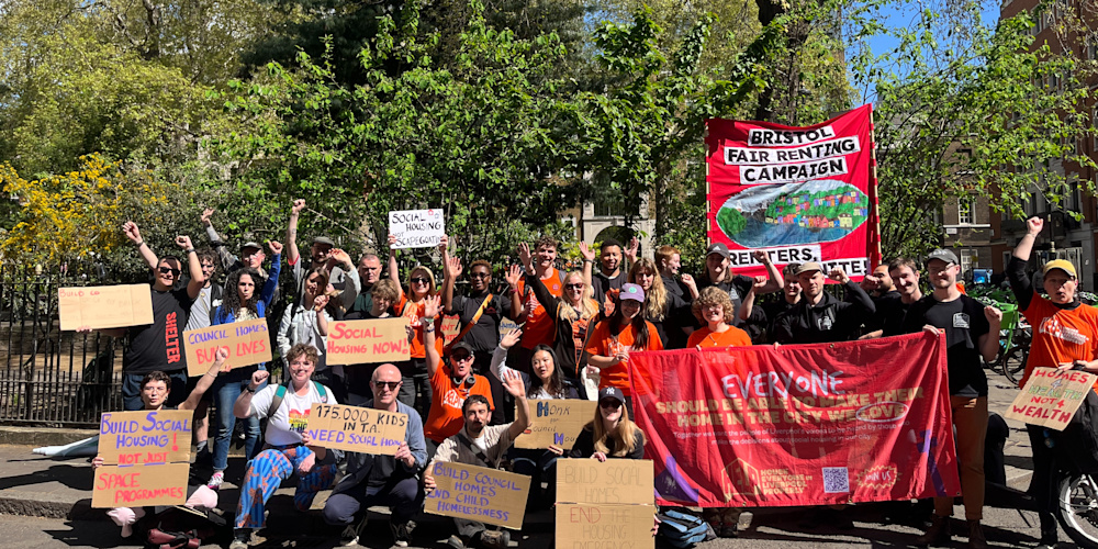 A group of campaigners at the national housing demonstration. They are all standing together and are holding up banners and placards, which call for more social homes and homes for health not wealth . There is also a Bristol Fair Renting campaign banner being held up by members of the campaign. 