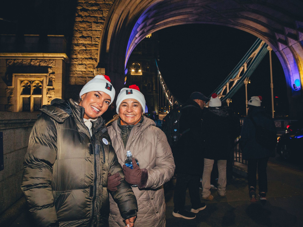 Two people wearing coats and bobble hats stand on a bridge on the Walk for Home route.