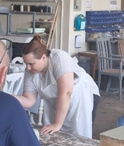 Vicki wearing white overalls and painting a chest of drawers