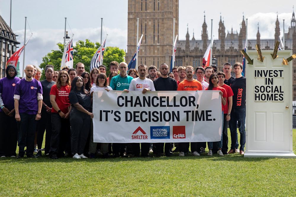A group of Shelter campaigners outside the Houses of Parliament holding banners that read 'Chancellor, it's decision time', 'Invest in social homes'.