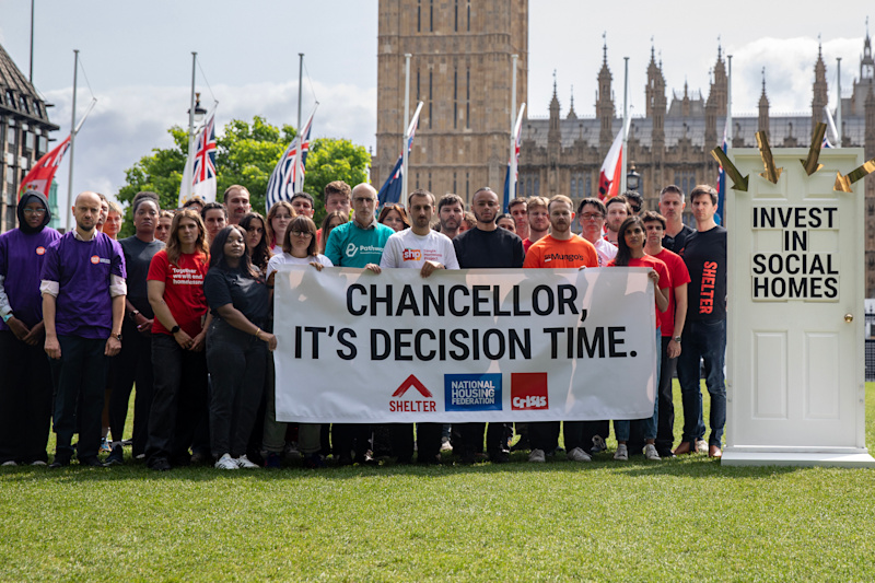 A group of Shelter campaigners outside the Houses of Parliament holding banners that read 'Chancellor, it's decision time', 'Invest in social homes'