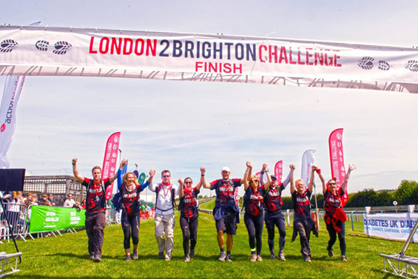 A group of happy participants holding hands as they cross the London 2 Brighton finish line