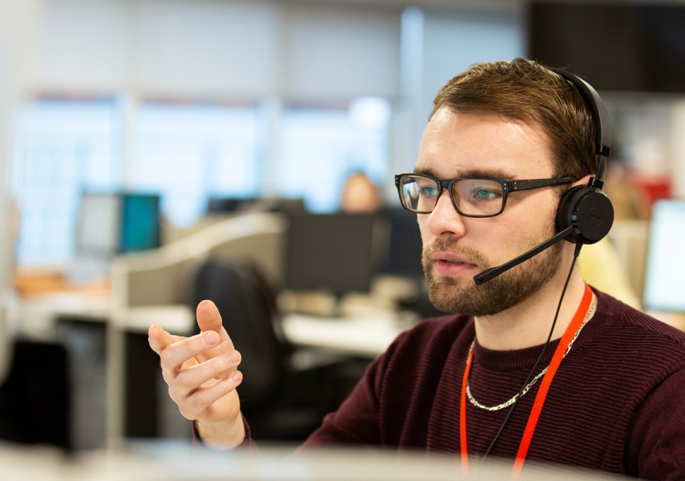 Adam from the Shelter advice line in Sheffield wears a headset and sits at a computer