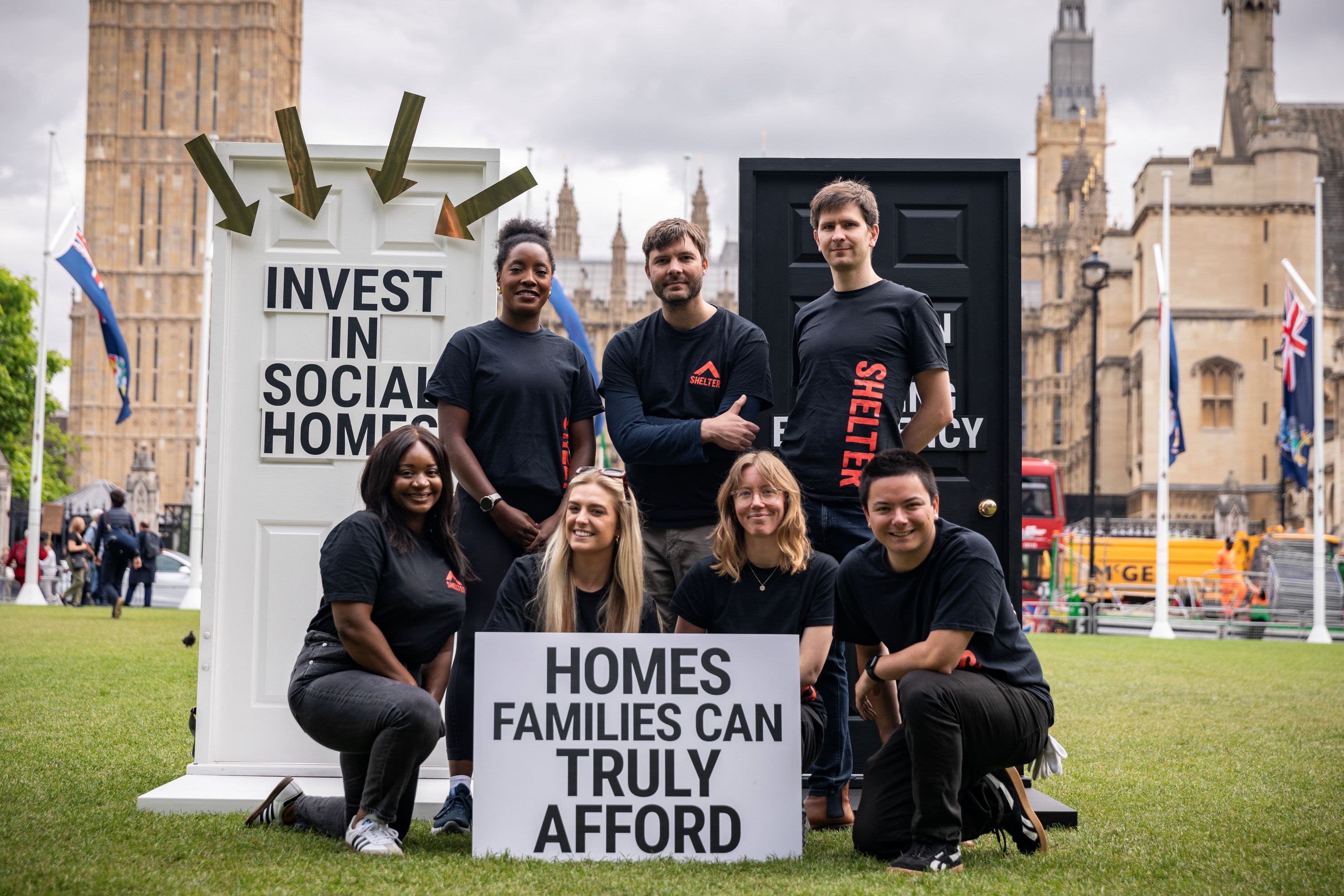 A group of Shelter campaigners in a square outside Westminster, holding signs that say 'Invest in social homes' and 'Homes families can truly afford'.