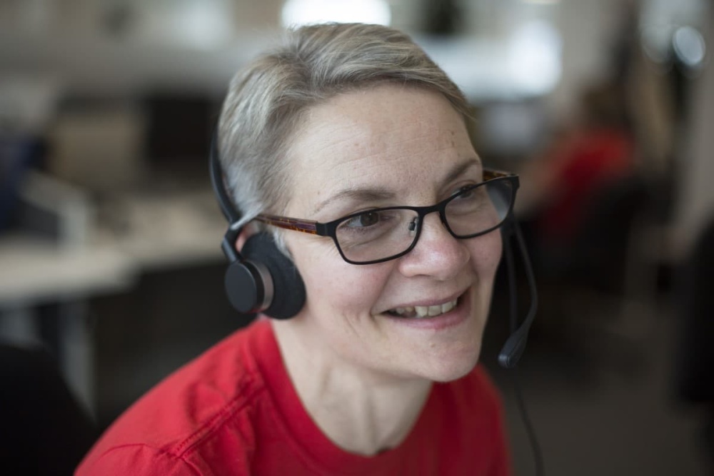 A female Shelter adviser, smiling while on the telephone with a client.