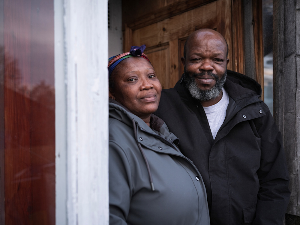 Picture of black couple standing by house doorway smiling