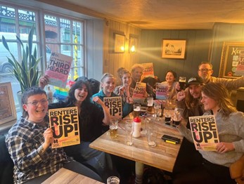 The Norwich Renters Collective sit at a table in April 2023, celebrating after the planning committee approved the Anglia Square development with only 10% affordable homes. 