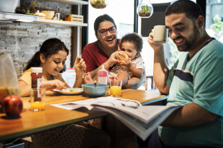 A family sitting around a table laughing together as they eat breakfast