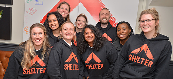 A crowd of smiling people wearing Shelter hoodies