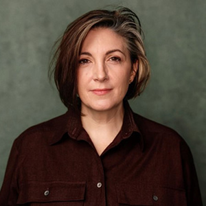 Helen MacNamara wears a black shirt and stands against a grey background.