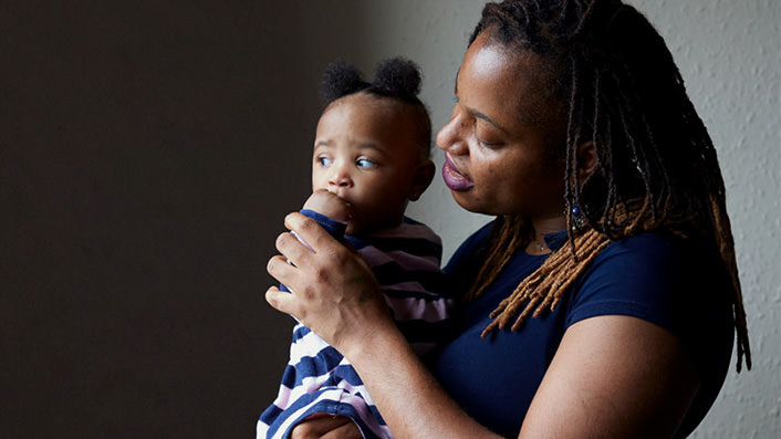 A mother smiling at her young child looking at the window