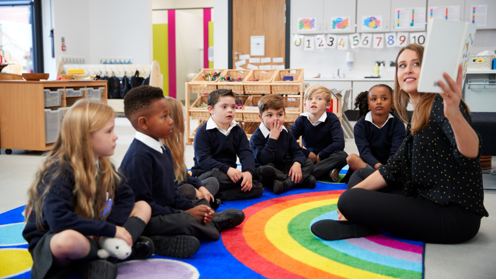 School teacher at the front of her class teaching young pupils 