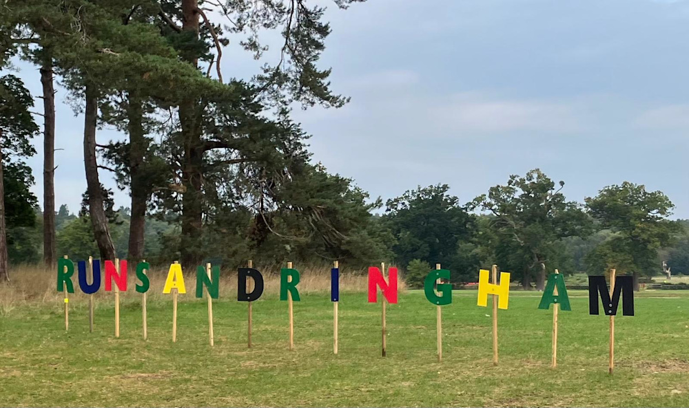 Wooden Run Sandringham signage in multiple colours is planted in the field at the Sandringham Half Marathon 2025. 