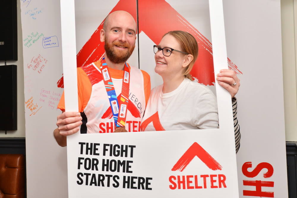 A man and a woman holding a shelter sign and posing for the camera with medals