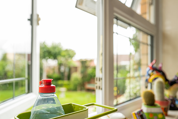 A bright kitchen windowsill with a bottle of washing up liquid in focus