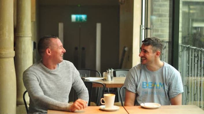 Two men have a conversation in a cafe