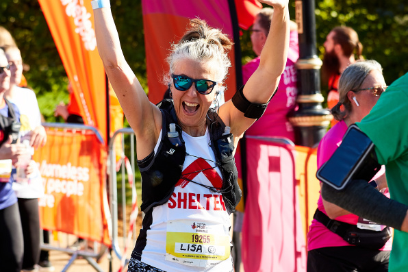 A Shelter Royal Half marathon female runner raises hands whilst smiling into camera