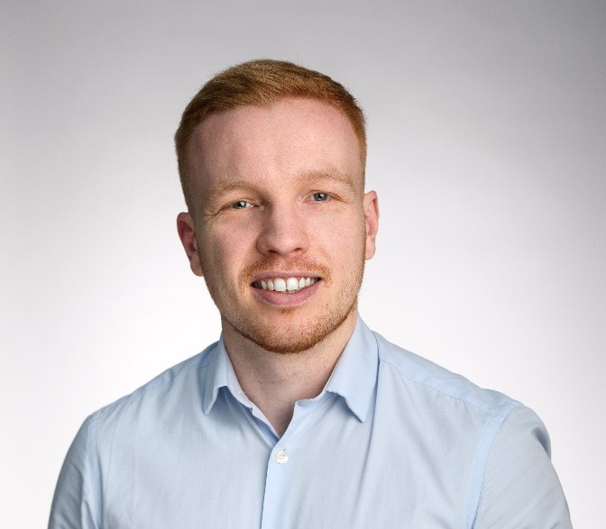 A headshot of Freddie wearing a smart shirt and smiling at the camera.