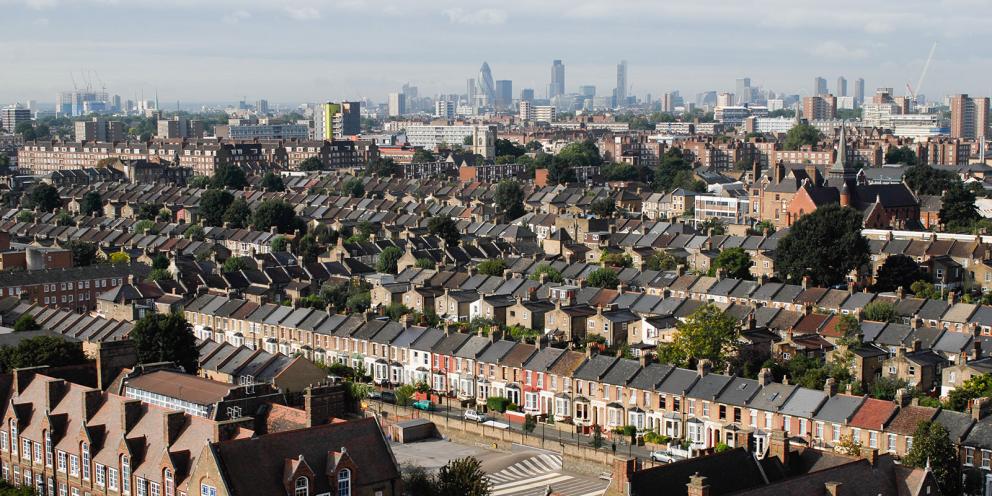 Aerial view of rows of houses in front of the tower blocks of London in the background
