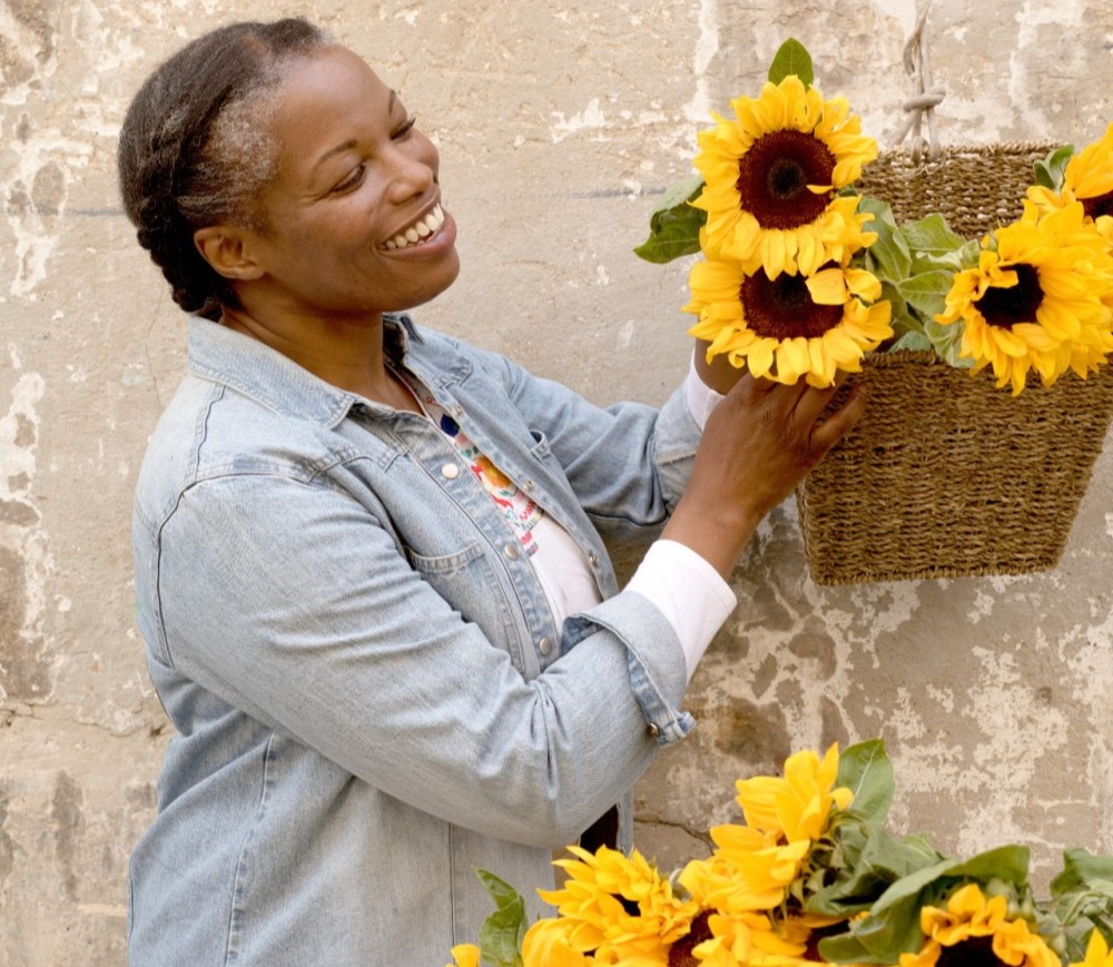A woman smiling next to a basket of sunflowers