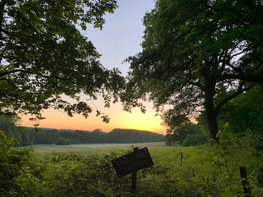 A beautiful sunrise view, with a way marker in the foreground and the coastline in the background.