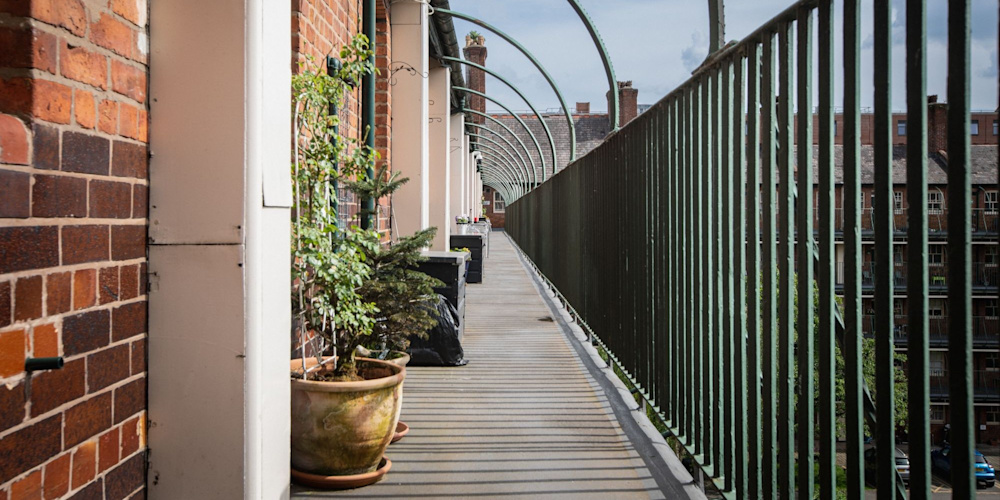 The balconies of a block of flats, which have potted plants and a view of the central courtyard.