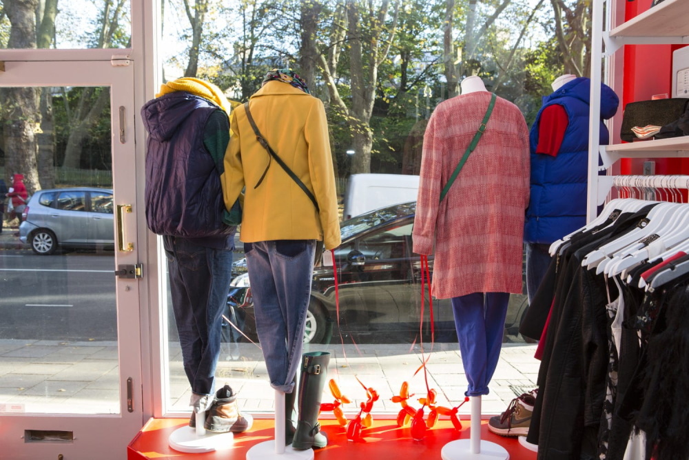 Mannequins wearing a colourful selection of clothes in the window of a Shelter shop