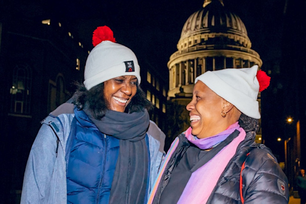 Two women wearing Shelter bobble hats take part in the Walk for Home London event. They are both smiling.