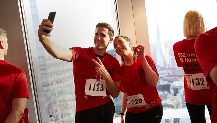 Two people take a selfie in a building, holding up their medal for Vertical Rush 