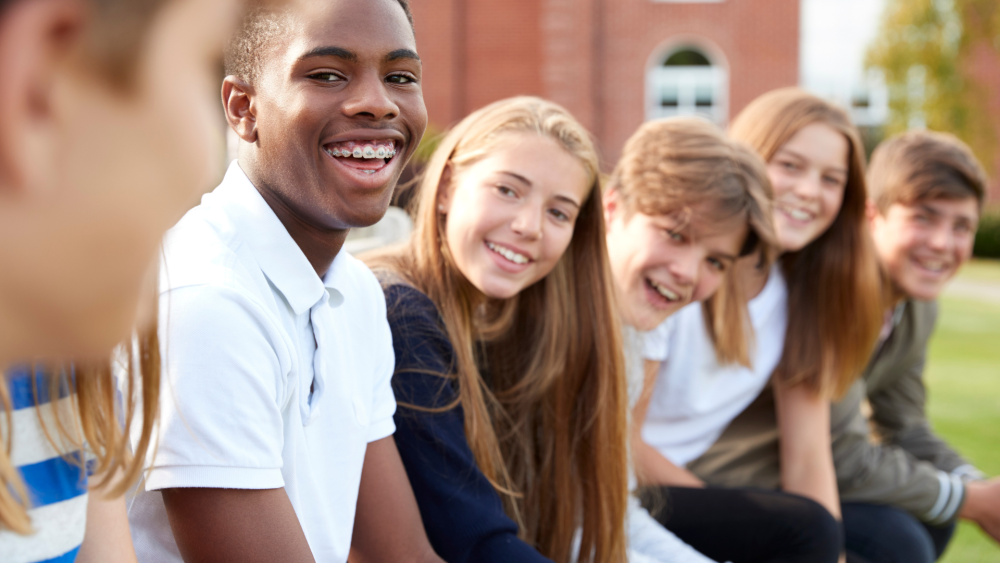 A group of young students in a row, smiling and supporting each other